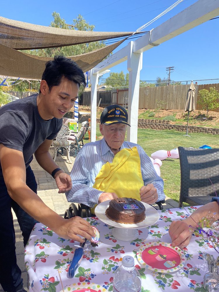 An outdoor celebration featuring a cake and family members gathered around.