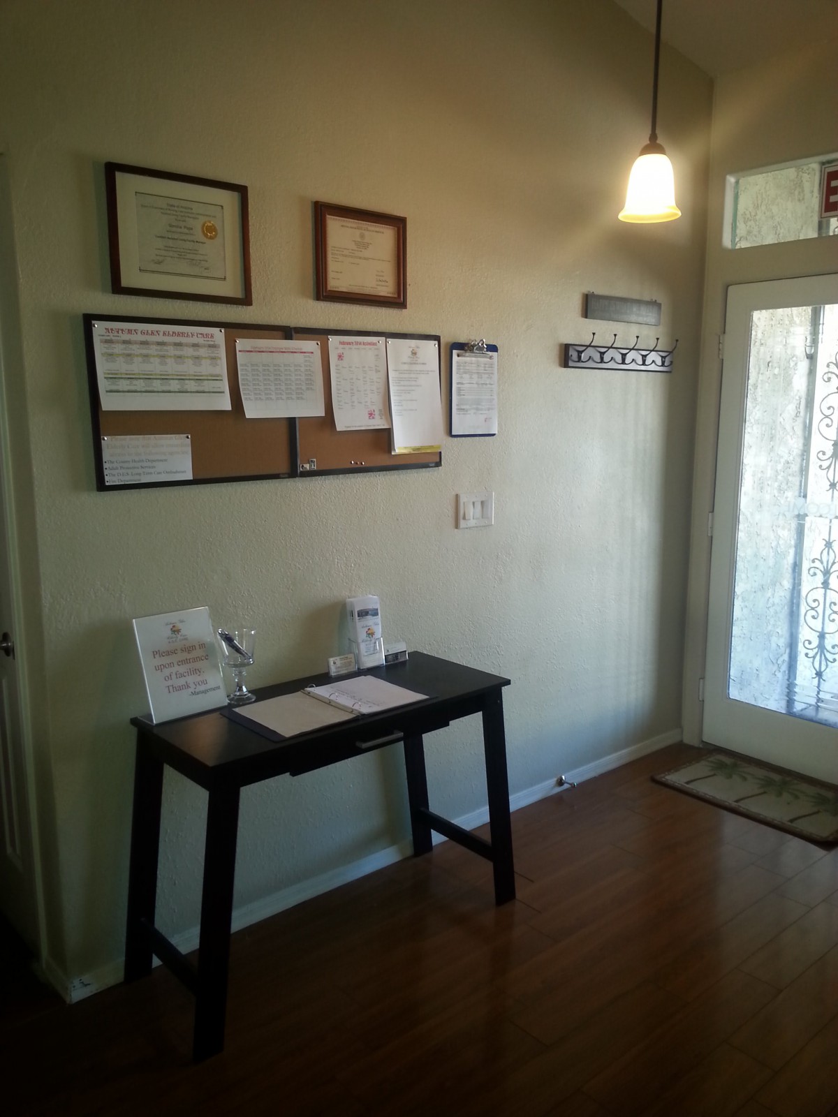 A small entryway with a desk, bulletin board, and documents on display.