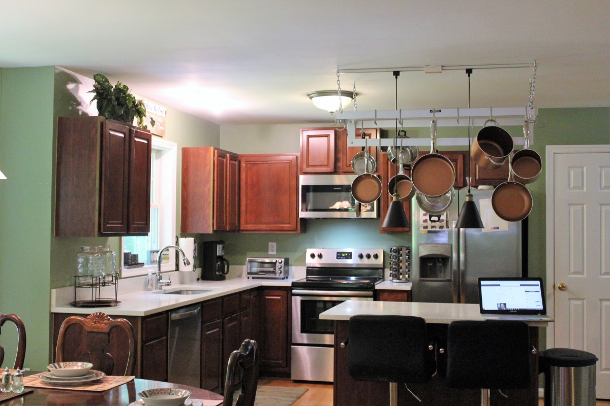 A modern kitchen with stainless steel appliances, featuring a central island and hanging pots and pans.