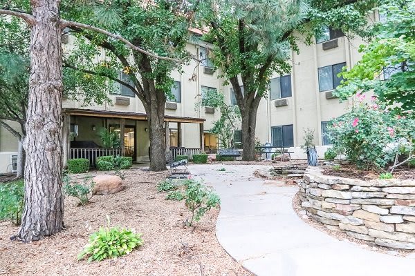A landscaped outdoor area with trees and a pathway leading to a building.