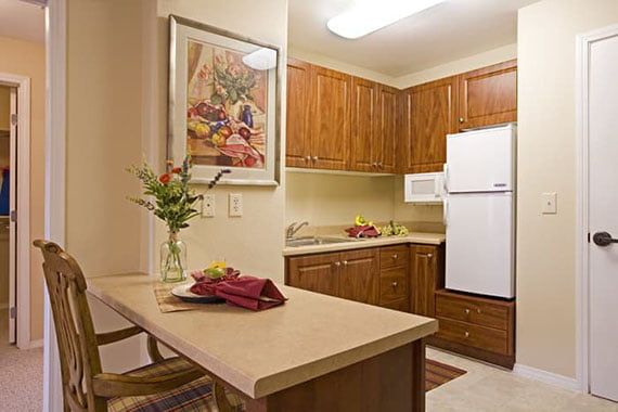 A cozy kitchen with wood cabinets, a countertop dining area, and a refrigerator.
