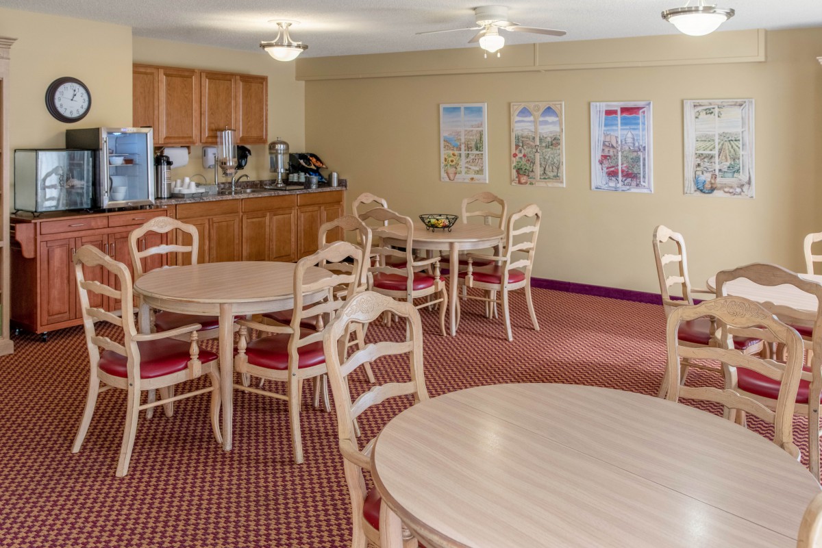 A cozy dining area with multiple tables and chairs, featuring a coffee station in the corner.