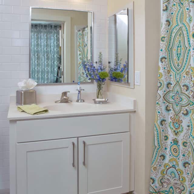 A tidy bathroom with a vanity, mirror, and colorful shower curtain.