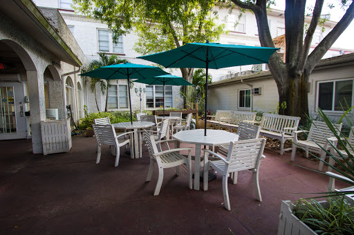 A cozy outdoor patio area with white furniture and teal umbrellas, perfect for enjoying a peaceful moment.