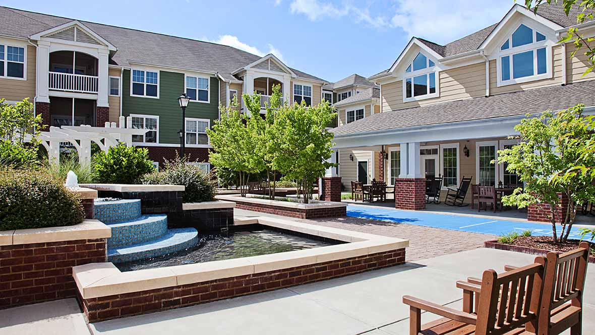 An inviting courtyard featuring a water fountain and seating areas surrounded by modern apartment buildings.