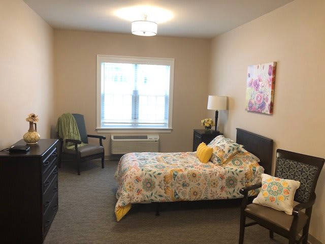 A cozy bedroom with a single bed, a chair, and decorative elements.