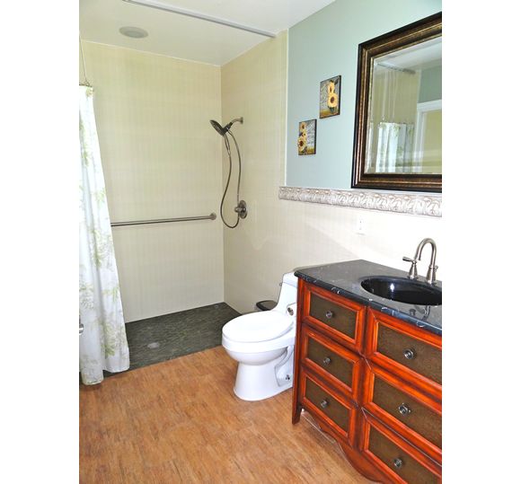 A modern bathroom with a shower, toilet, and a wooden vanity with a sink.