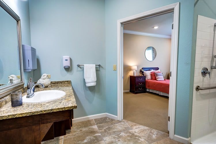 A cozy home interior featuring a bathroom leading into a warmly decorated bedroom.