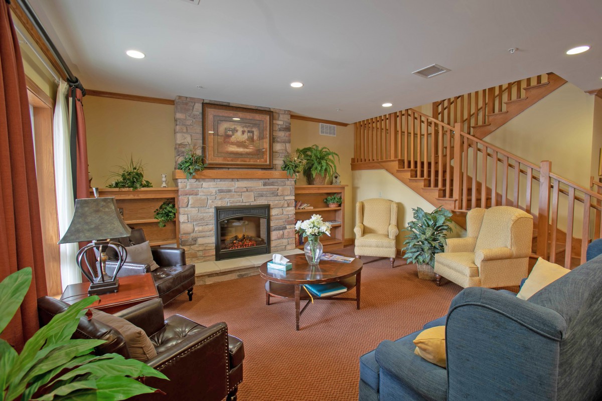 A cozy living room featuring a fireplace, comfortable seating, and a wooden staircase.
