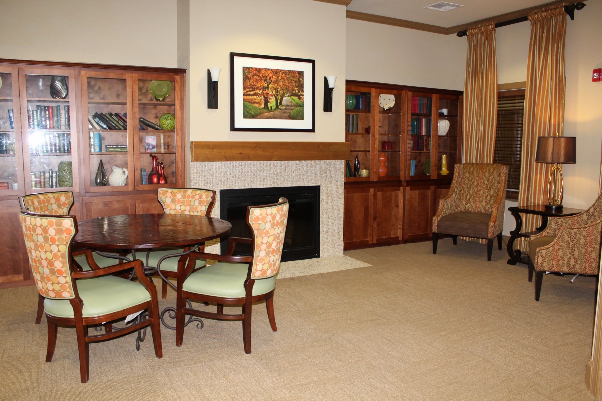 A cozy living room with a fireplace, dining table, and bookshelves.