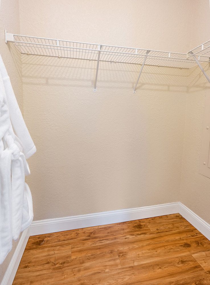 An empty closet with wire shelving and a robe hanging inside.