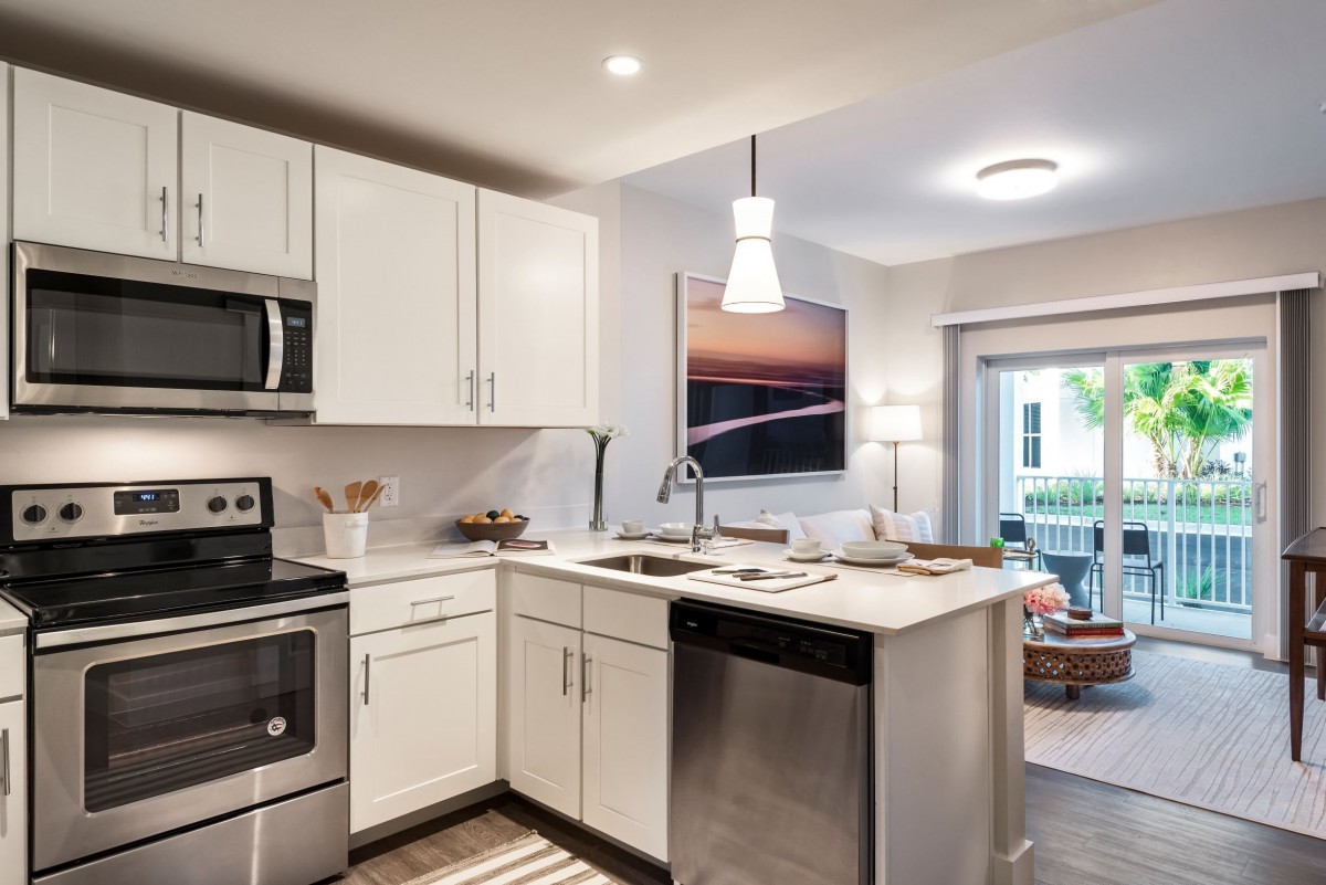 A modern kitchen with white cabinets and stainless steel appliances, featuring a cozy dining area.