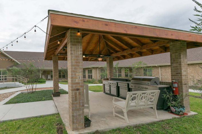 A cozy outdoor gazebo with brick columns and seating, perfect for gatherings.