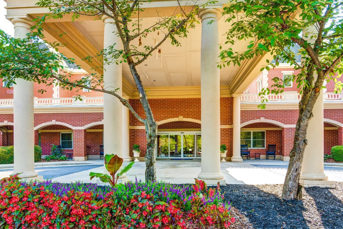 A beautifully landscaped building entrance with large columns and vibrant flowers.