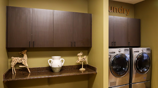 A stylish and modern laundry room featuring storage cabinets, a decorative vase, and a washing machine.