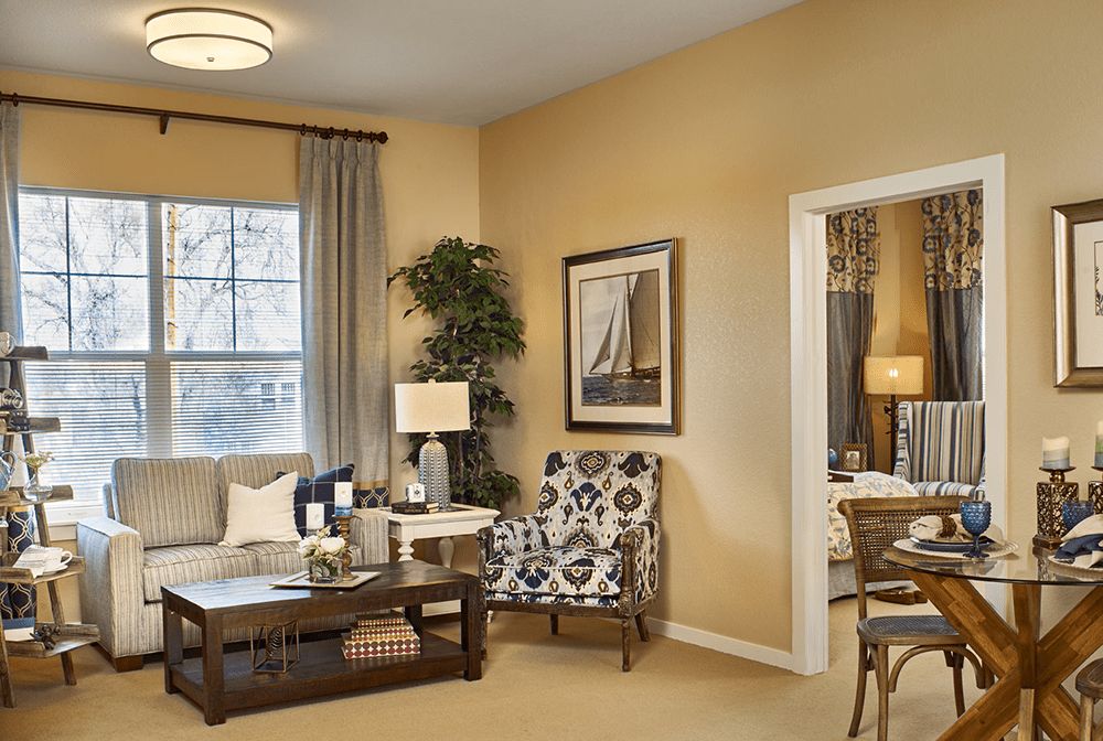 A cozy and stylish living room with modern decor, featuring a comfortable sofa, patterned armchair, elegant coffee table, and framed artwork.