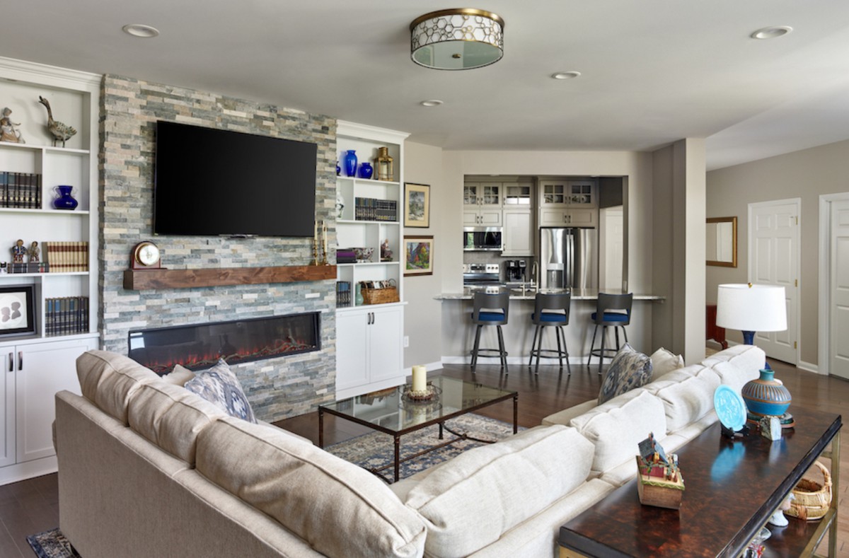 Modern living room with a stone fireplace, open kitchen, and contemporary decor.