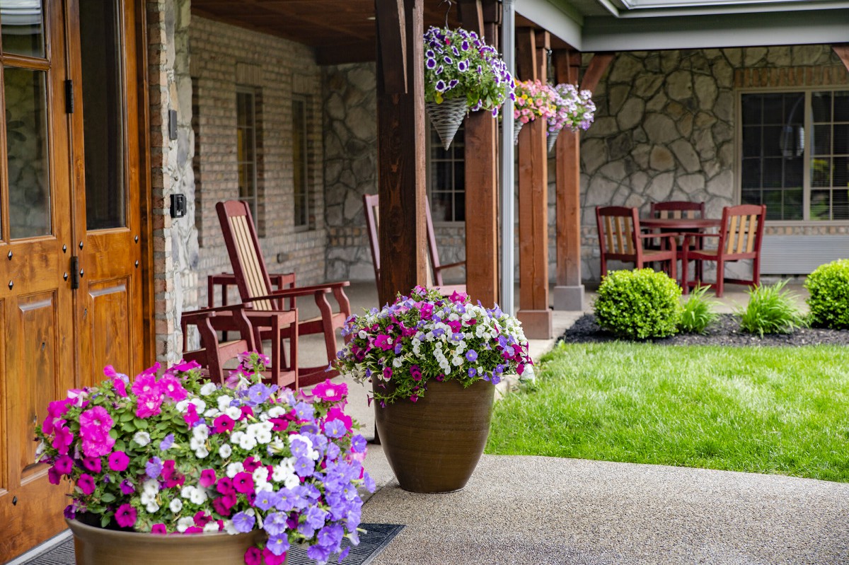 A charming garden patio with vibrant flowers and comfortable wooden seating.