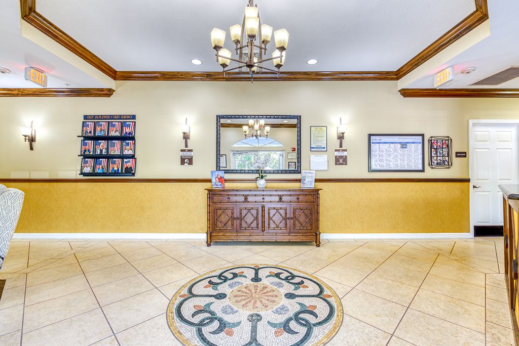 Elegant lobby area with a chandelier, reception desk, and decorative floor design.