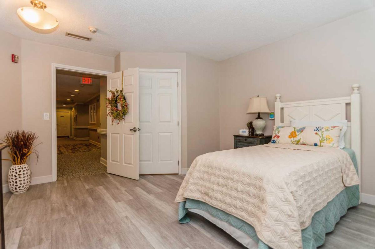 A cozy bedroom with a neatly made bed and a lamp on the nightstand.