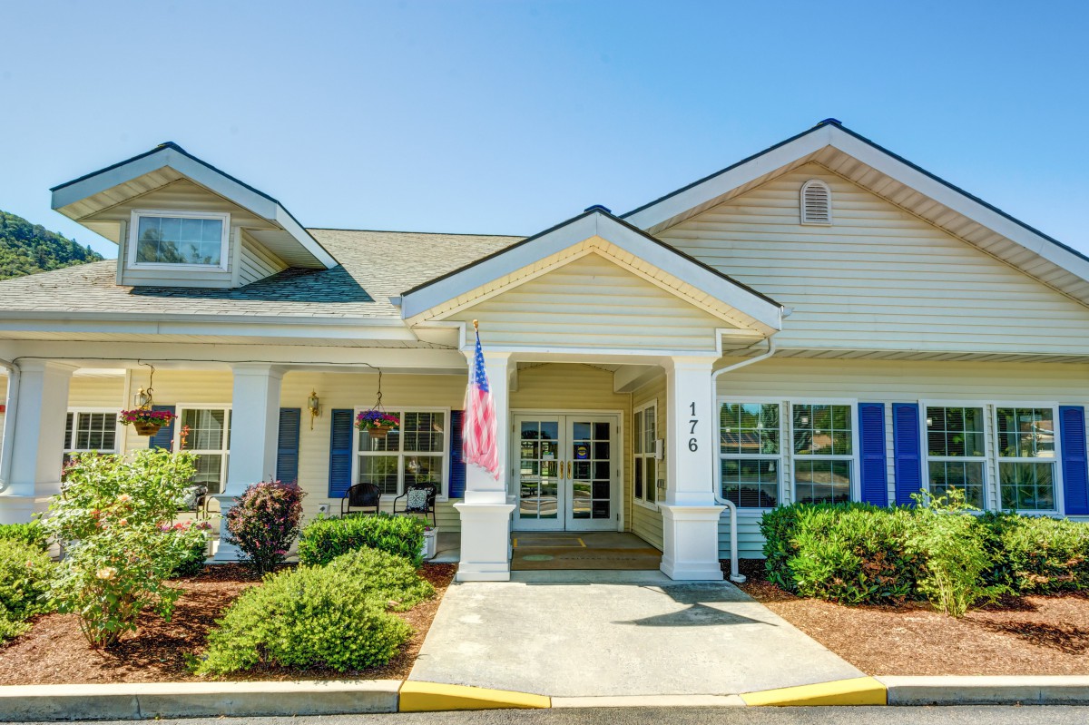 A welcoming entrance of a residential building with neatly landscaped surroundings and an American flag on display.