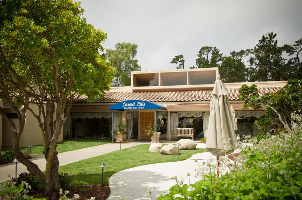 A welcoming entrance of a building with an awning, surrounded by trees and greenery.