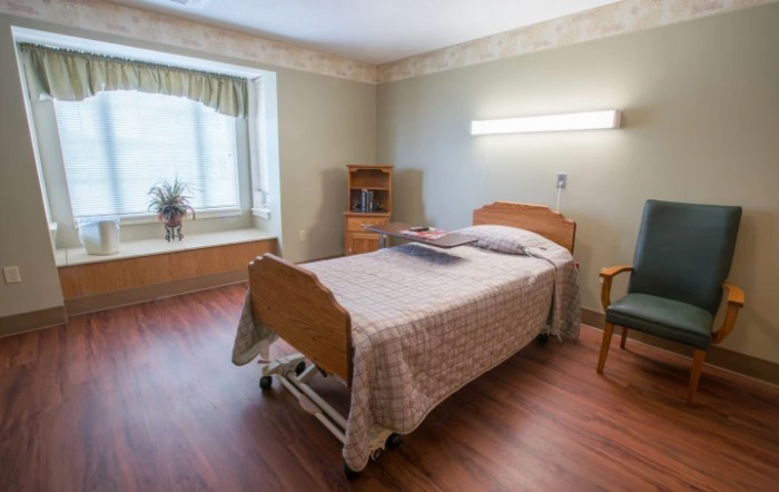 A clean and organized hospital room with a single bed and essential furniture.