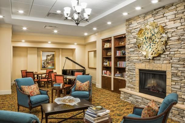 A cozy living room with a fireplace, bookshelf, and piano.
