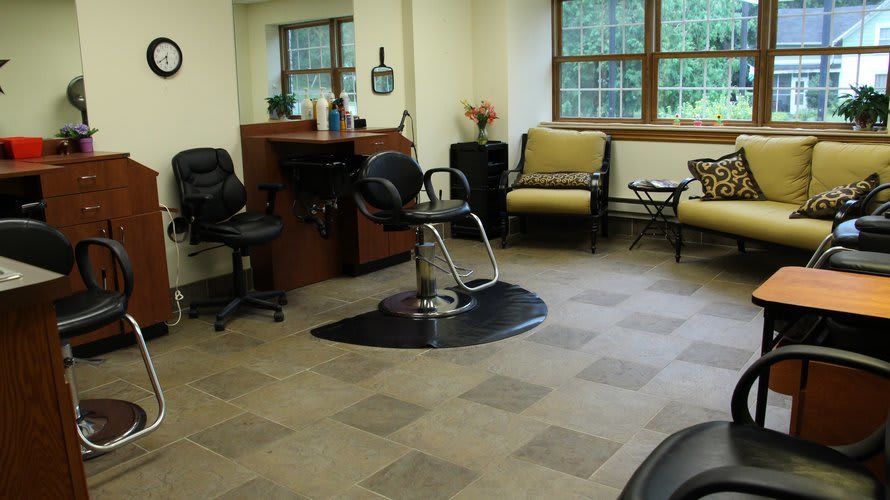 A cozy hair salon interior featuring styling chairs, a mirror, and a waiting area.
