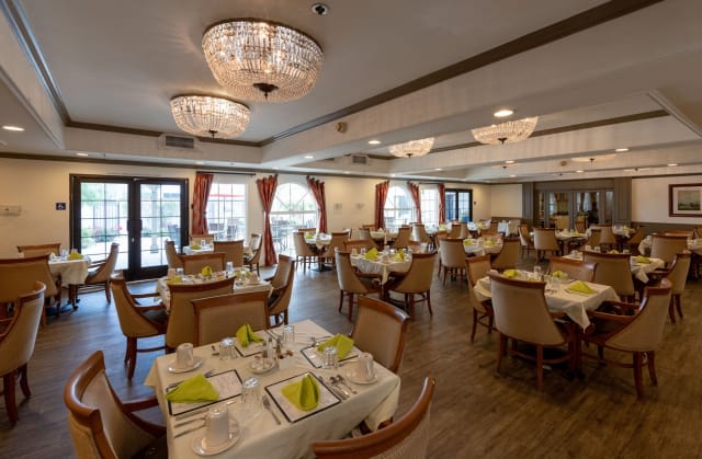 An elegant restaurant dining area featuring chandeliers and neatly set tables.