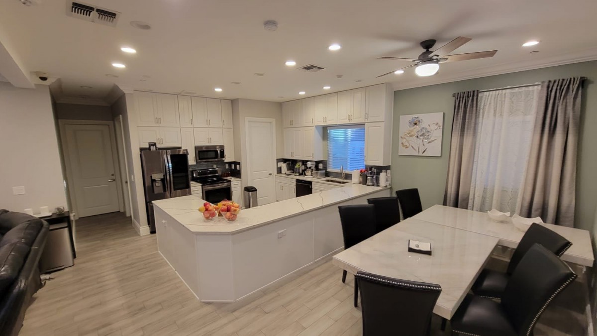 A modern open-concept kitchen and dining area with white cabinetry and an island counter.