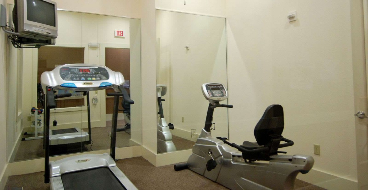 A small gym room with a treadmill and stationary bike.