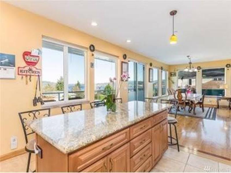 A spacious kitchen with a granite island, large windows, and a dining area bathed in natural light.
