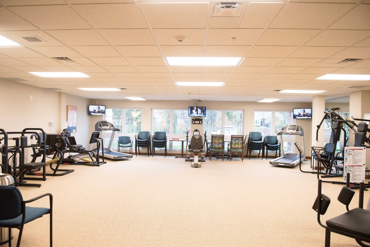 A well-lit gym with assorted fitness equipment and seating area.