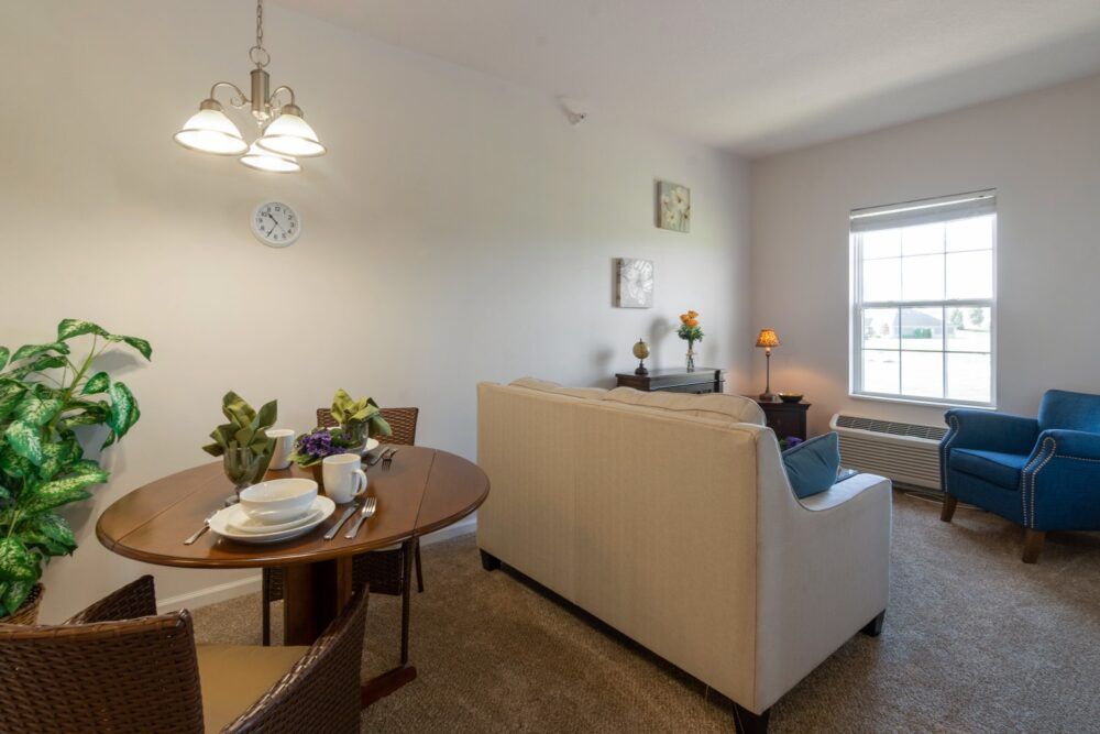 A cozy living and dining area with a sofa, table set, and natural light from the window.