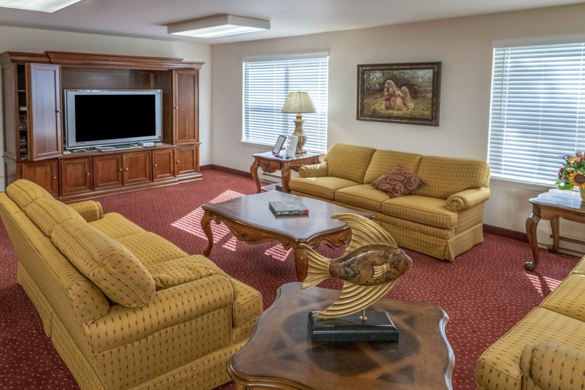 A cozy living room with yellow sofas, a large wooden entertainment center, and decorative elements.
