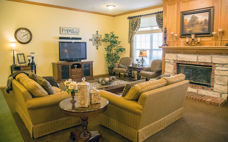 A cozy living room with sofas arranged around a coffee table, a television on a stand, and a fireplace.