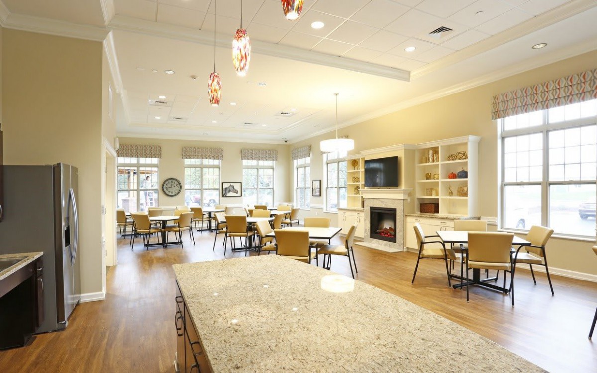 A spacious and modern dining area with multiple tables, chairs, a large fireplace, and ample natural light from the windows.