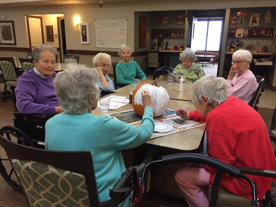 A group of seniors gathered around a table engaged in a crafting activity.