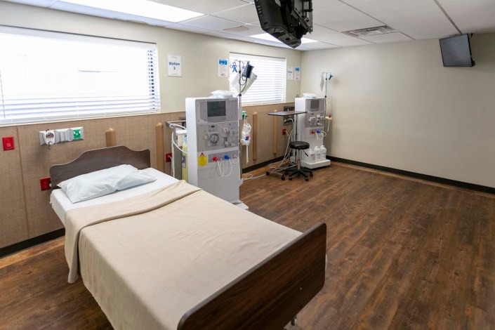 A hospital room equipped with dialysis machines and a bed.