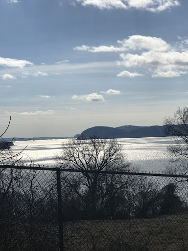 A serene view of the water reflecting the clouds and distant hills.