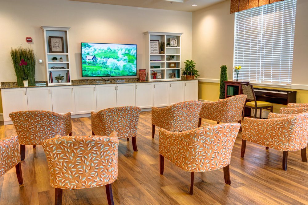 A cozy living room with comfortable chairs facing a television, surrounded by bookshelves.