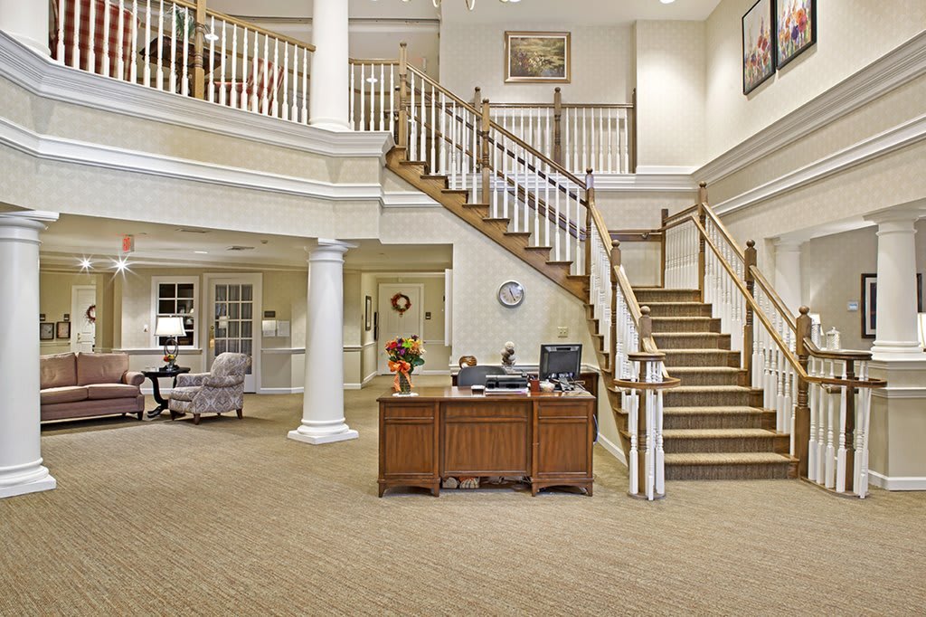 A spacious lobby with a grand staircase and reception desk.