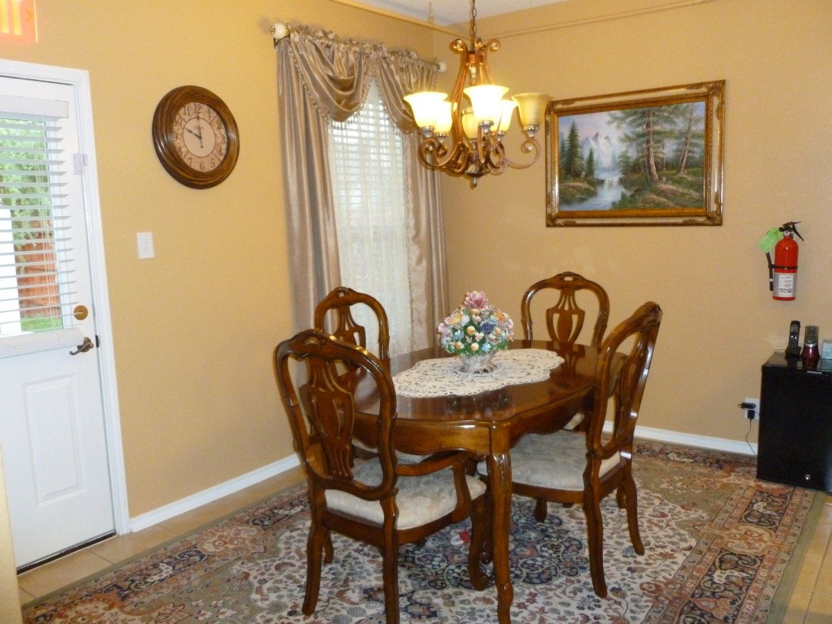 A traditional dining room with a wooden table set, ornate chandelier, and decorative wall art.