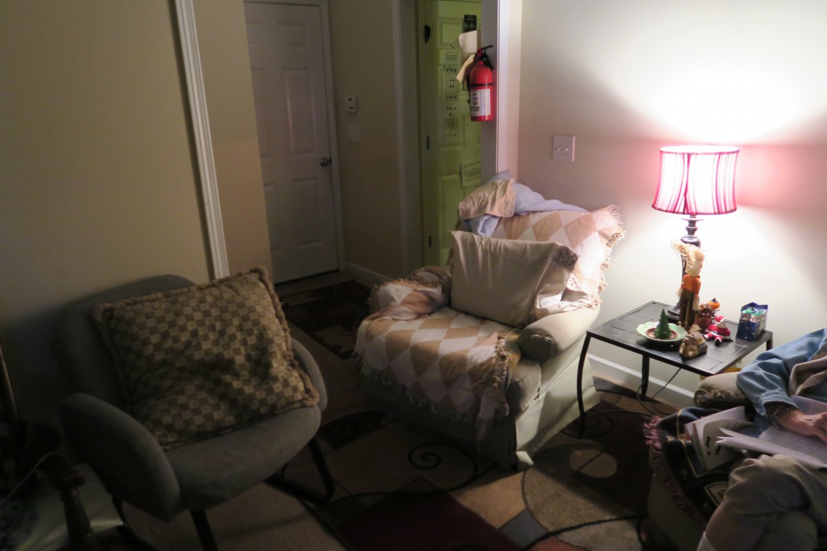 A cozy living room setting with an armchair and a softly lit lamp.