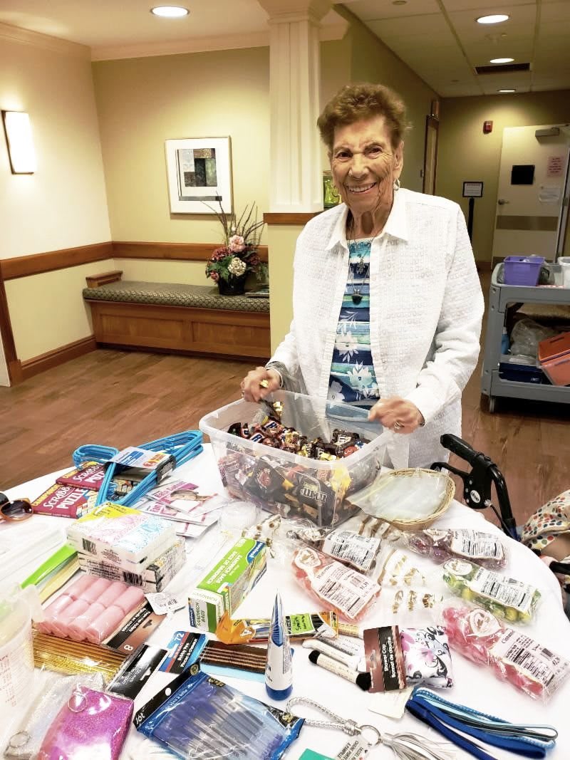 A woman organizing donations and snacks on a table indoors.