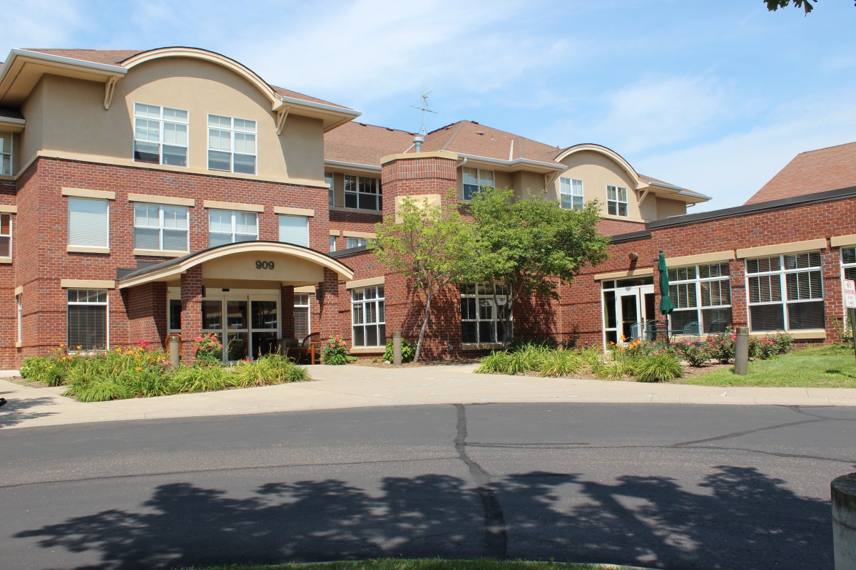 A modern brick residential building with trees and a clear sky.