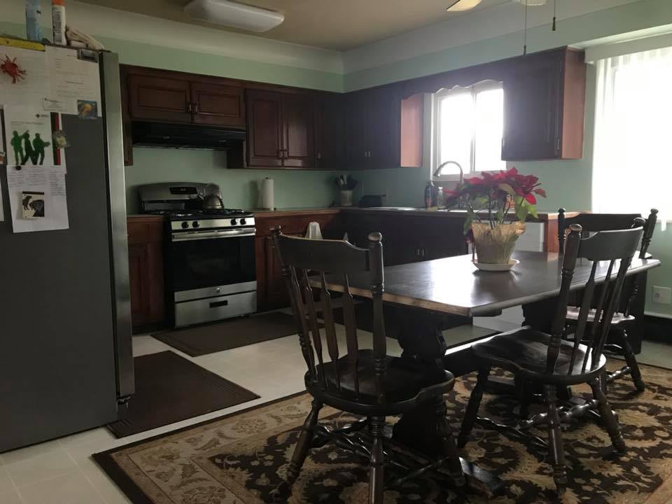 A cozy kitchen with a dining table and chairs, featuring modern appliances and wooden cabinets.
