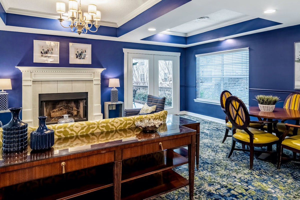 A stylish living room with blue walls, featuring a fireplace and elegant furniture.