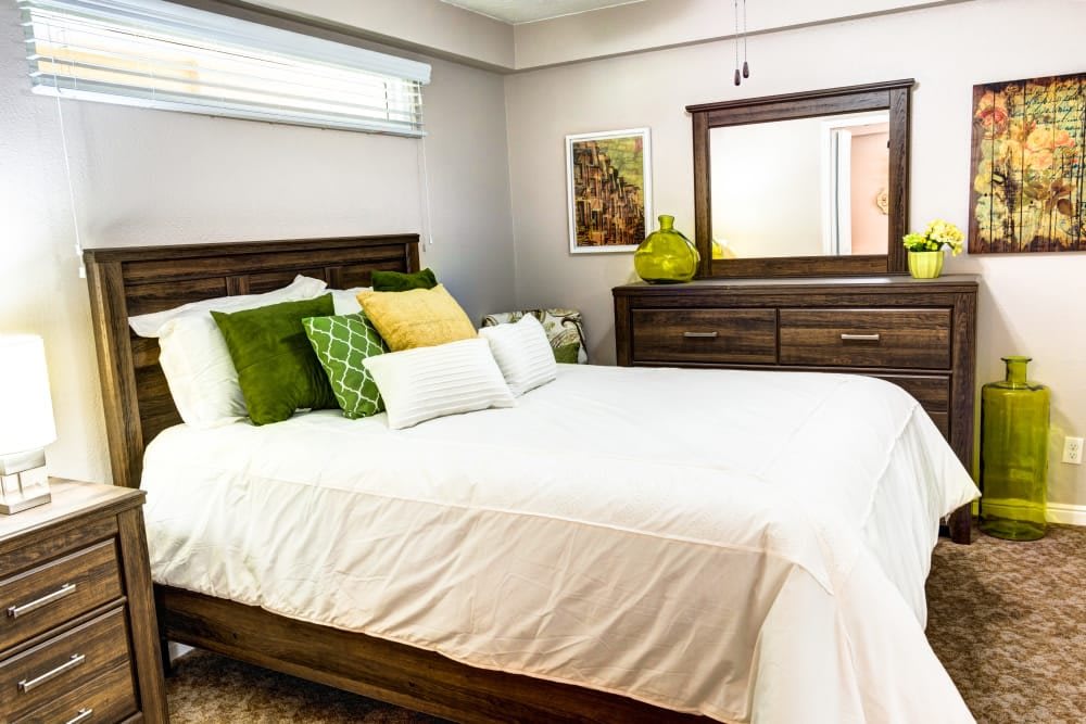 A modern bedroom with stylish wooden furniture and colorful pillows on a neatly made bed.